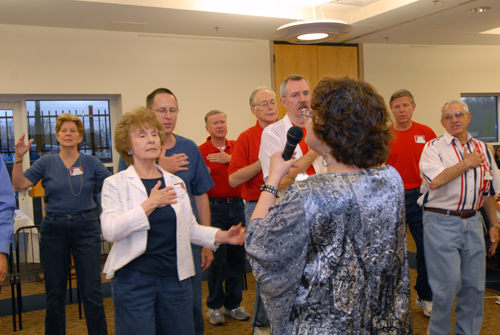 A woman leads a group of older men and women through an acting exercise